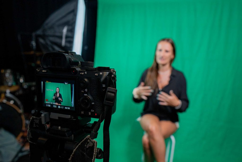 Woman in front of green screen with camera at front